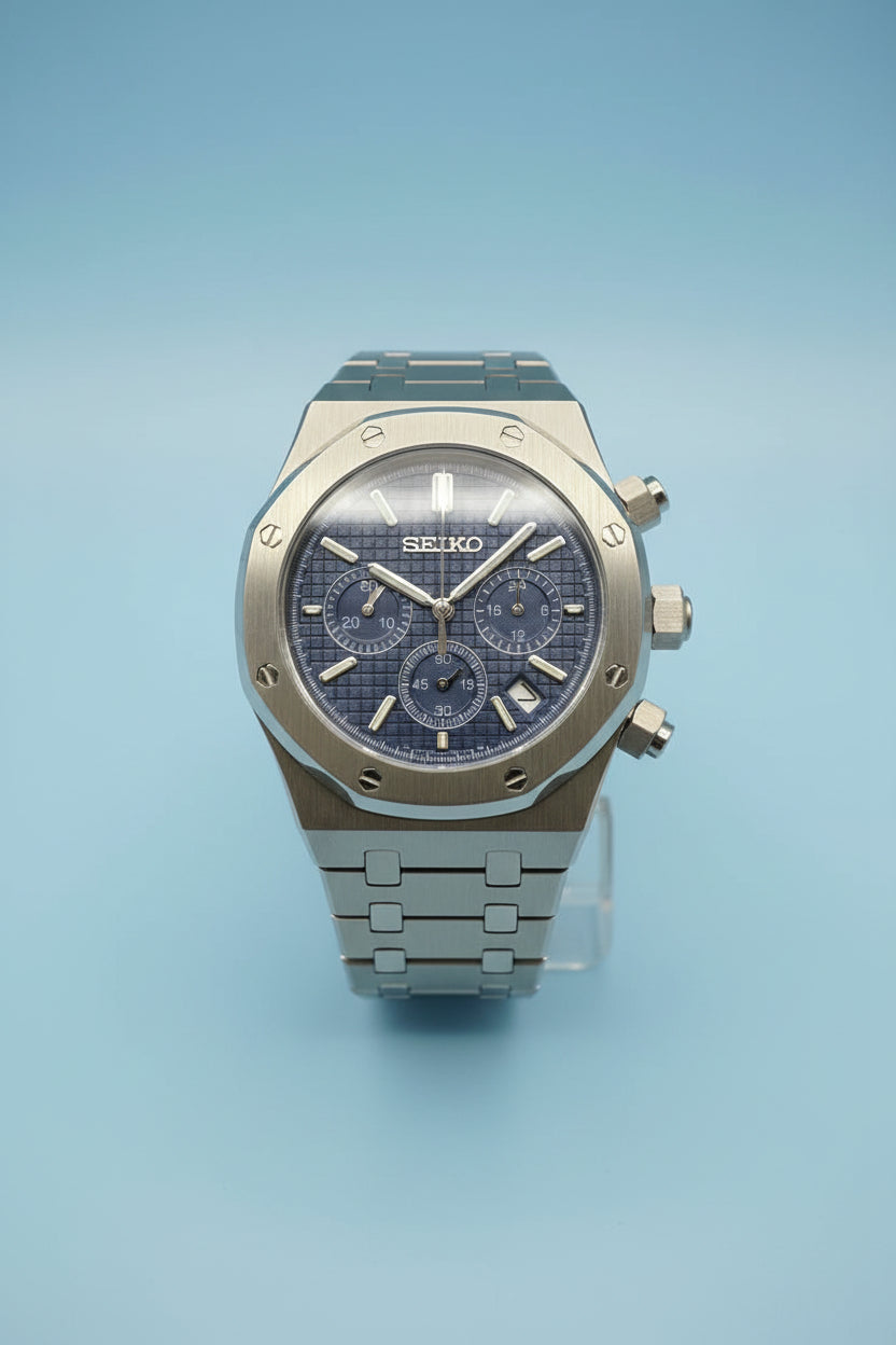 A Seiko Royal Oak chronograph watch with a blue dial and a silver-toned stainless steel case and bracelet, photographed against a dark gray background.