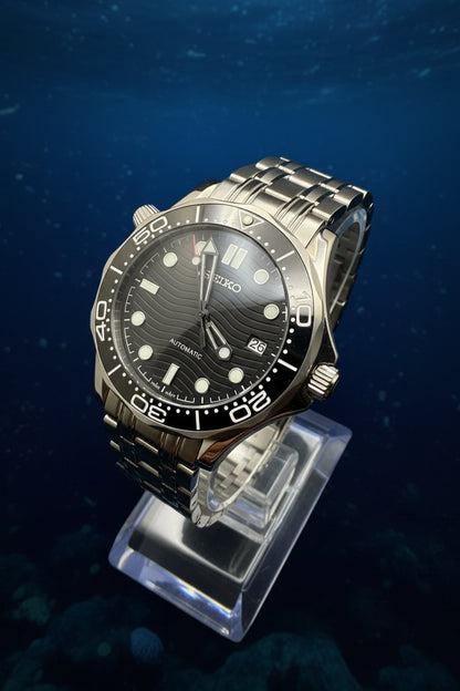 Wristwatch with black dial and silver metal band on a dark background