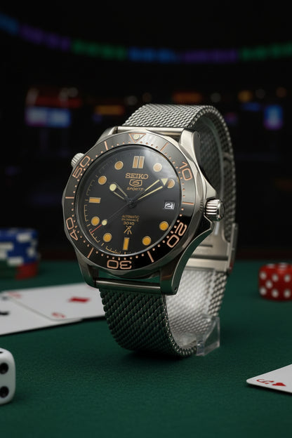A Seiko James bond wristwatch with a black dial, black bezel, and a silver-toned mesh metal bracelet, photographed against a dark gray background.