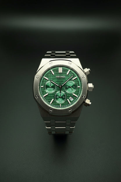 A Seiko wristwatch with a silver-tone metal case and bracelet, featuring a textured green dial with three subdials and green accents.