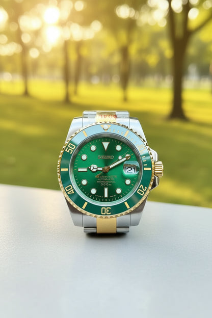 Green watch with silver and gold accents held in a hand against a blurred background