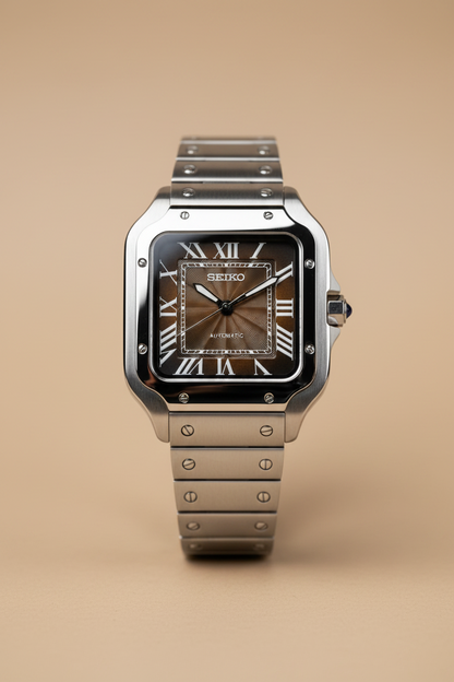 A Seiko Santos watch with a silver-tone stainless steel case and bracelet, featuring a brown sunburst dial with Roman numeral hour markers, resting on a dark surface next to a book.