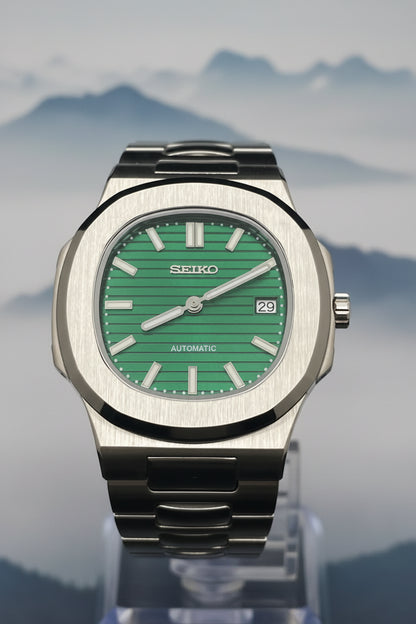 A Seiko automatic wristwatch with a brushed silver-tone metal case and a vibrant green dial, shown against a dark background.