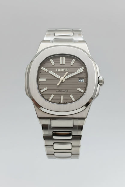 Silver Seiko watch held in a hand with a blurred background