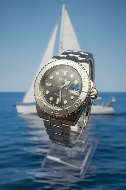 A stainless steel wristwatch with a dark gray dial, a rotating bezel, and a matching steel link bracelet, photographed on a dark gray background.