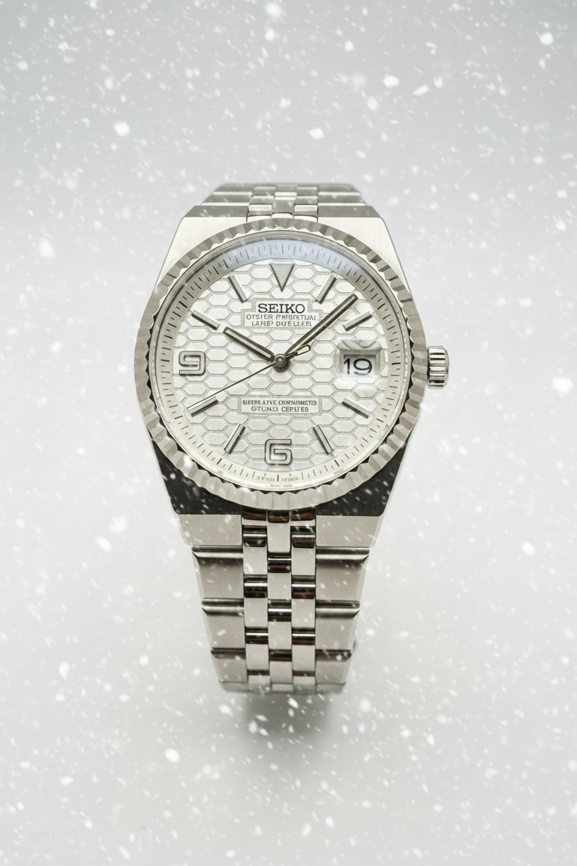 A Seiko stainless steel wristwatch with a textured silver dial, fluted bezel, and matching steel link bracelet, photographed against a dark gray background.