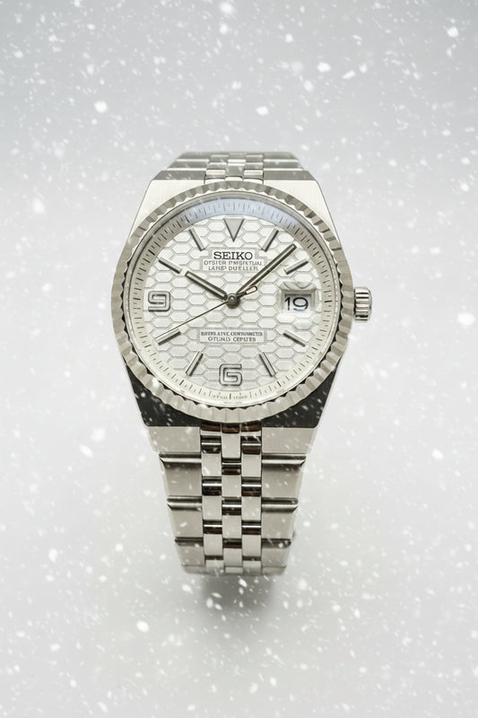 A Seiko stainless steel wristwatch with a textured silver dial, fluted bezel, and matching steel link bracelet, photographed against a dark gray background.