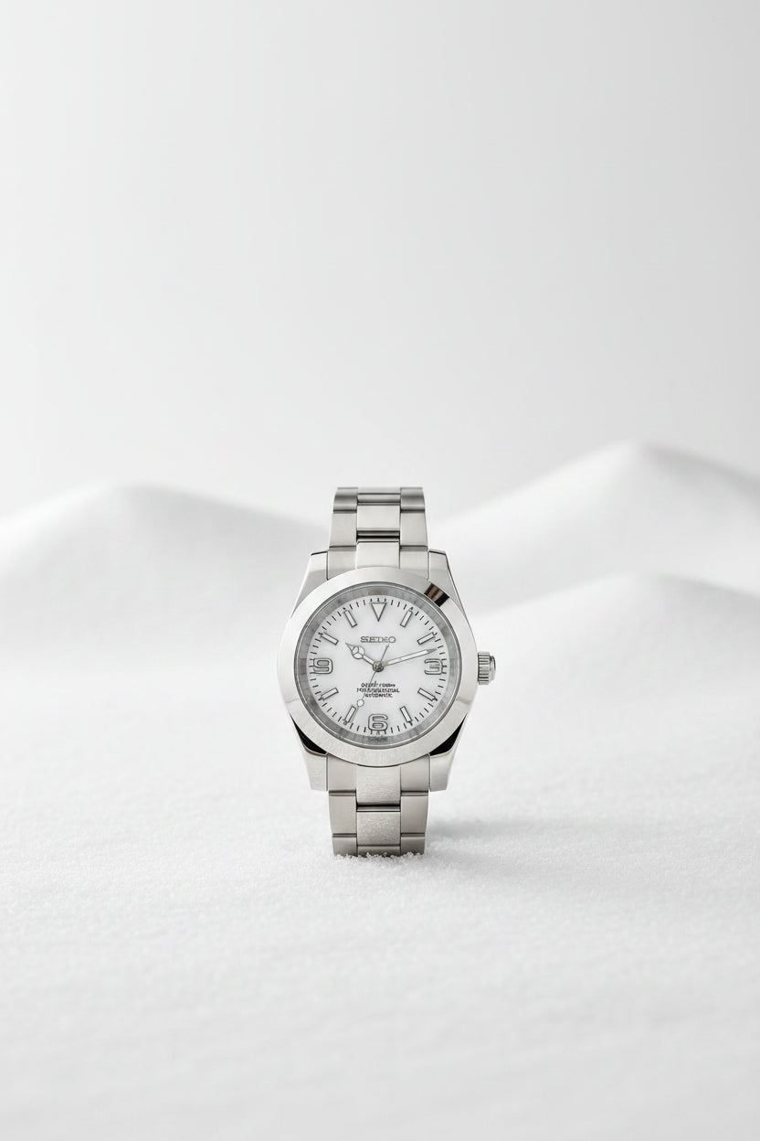 A Seiko stainless steel wristwatch with a white dial and silver-tone metal bracelet, displayed on a black textured surface.