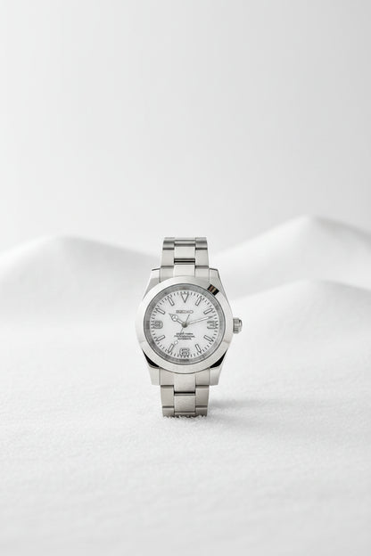 A Seiko stainless steel wristwatch with a white dial and silver-tone metal bracelet, displayed on a black textured surface.